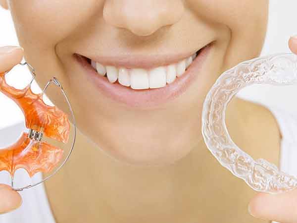 young woman holding two types of retainers